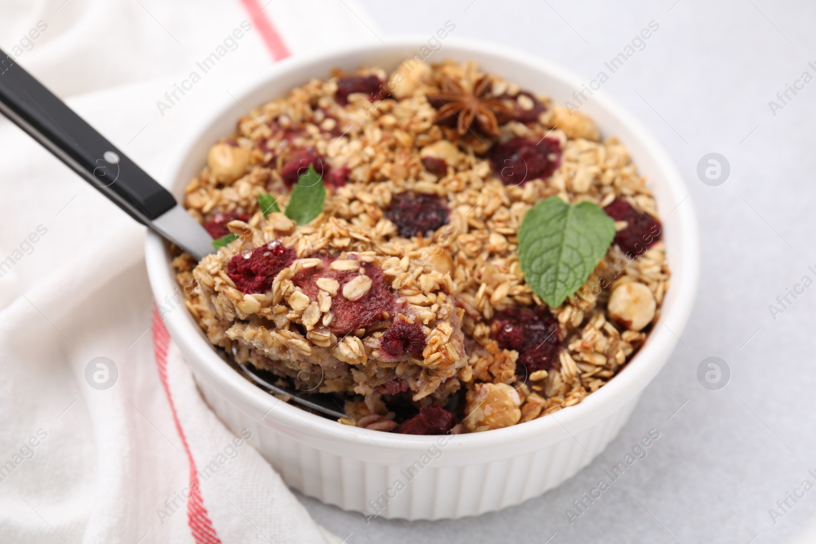Photo of Tasty baked oatmeal with berries and nuts on light table, closeup
