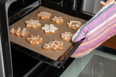 Photo of Woman taking baking tray with tasty Christmas cookies out of oven