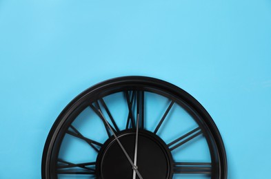 Photo of Stylish analog clock hanging on light blue wall, space for text. New Year countdown