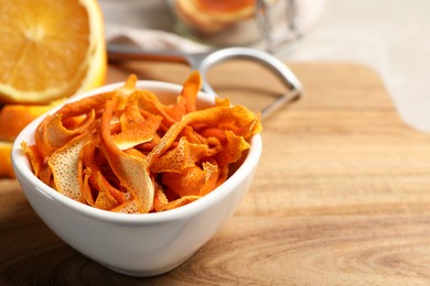 Photo of Dry orange peels and fresh fruit on wooden board, closeup