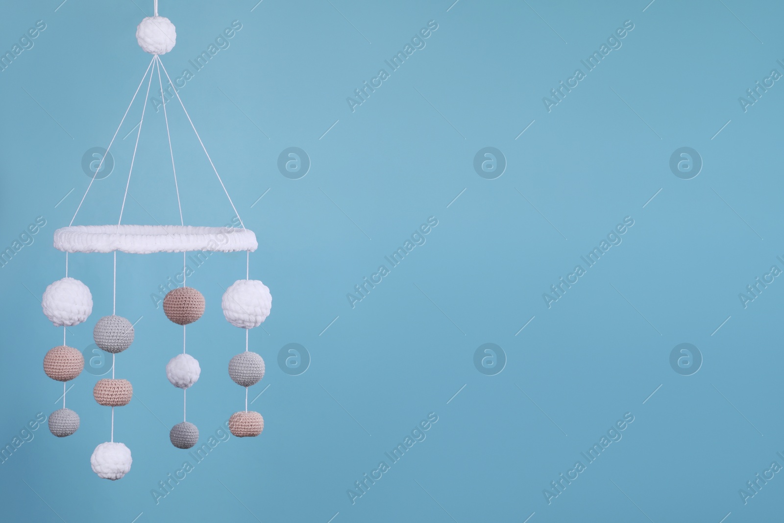 Photo of Cute baby crib mobile on light blue background, space for text