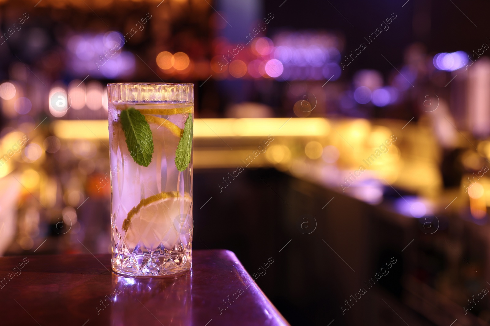 Photo of Fresh alcoholic cocktail on counter in bar. Space for text