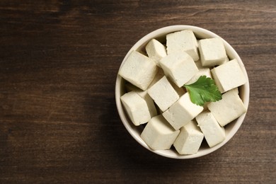 Delicious tofu with parsley on wooden table, top view. Space for text