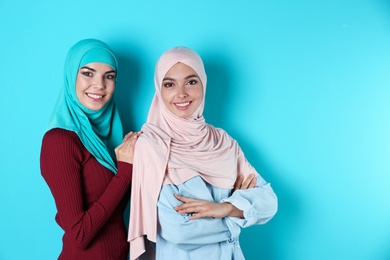 Portrait of young Muslim women in hijabs against color background