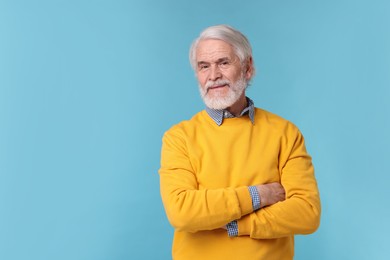 Portrait of stylish grandpa on light blue background, space for text