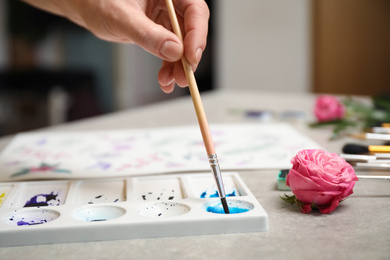 Woman painting with watercolor at grey stone table, closeup