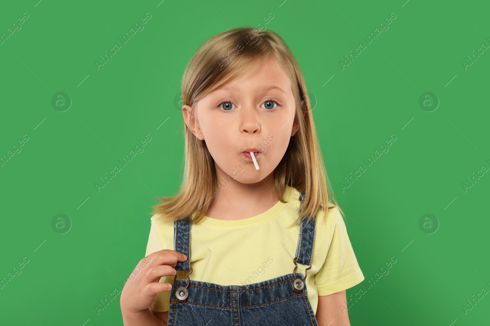 Photo of Portrait of cute girl with lollipop on green background