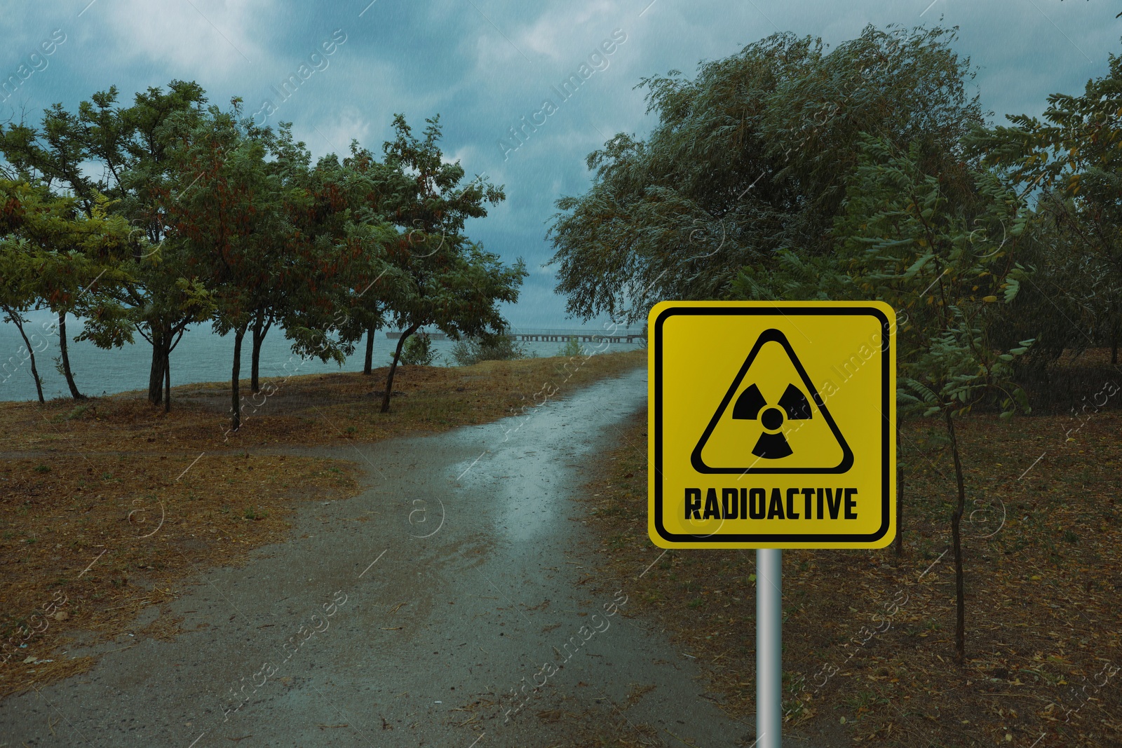 Image of Radioactive pollution. Yellow warning sign with hazard symbol in rural area