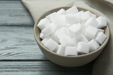 White sugar cubes in bowl on wooden table, closeup. Space for text