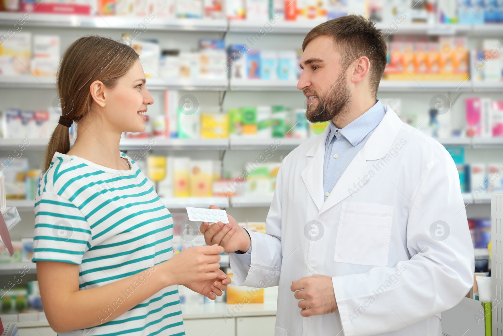 Image of Professional pharmacist giving pills to customer in modern drugstore