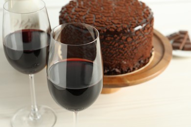 Photo of Delicious chocolate truffle cake and red wine on light table