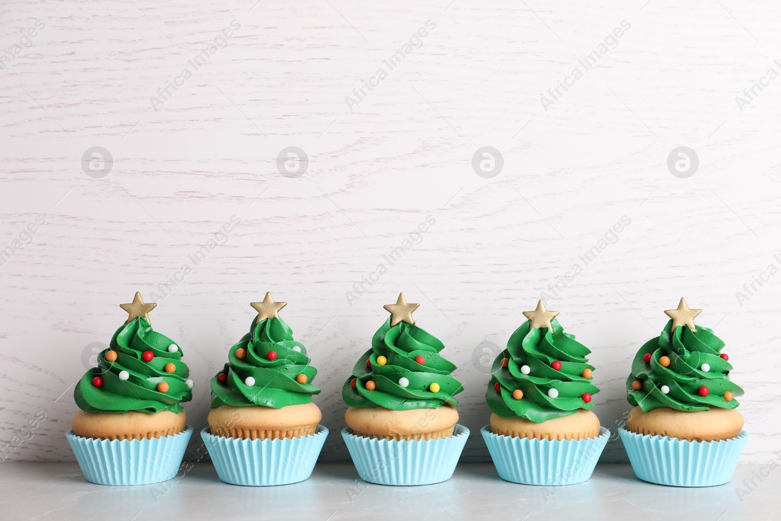 Photo of Christmas tree shaped cupcakes on table. Space for text