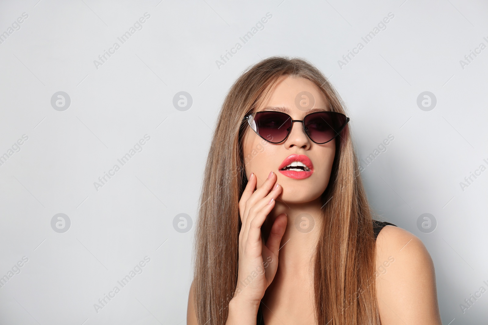 Photo of Young woman wearing stylish sunglasses on light background. Space for text