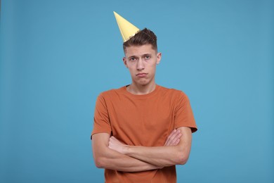 Photo of Sad young man in party hat on light blue background