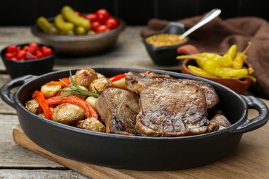 Photo of Tasty beef tongue pieces with potatoes, pepper and rosemary on wooden board, closeup