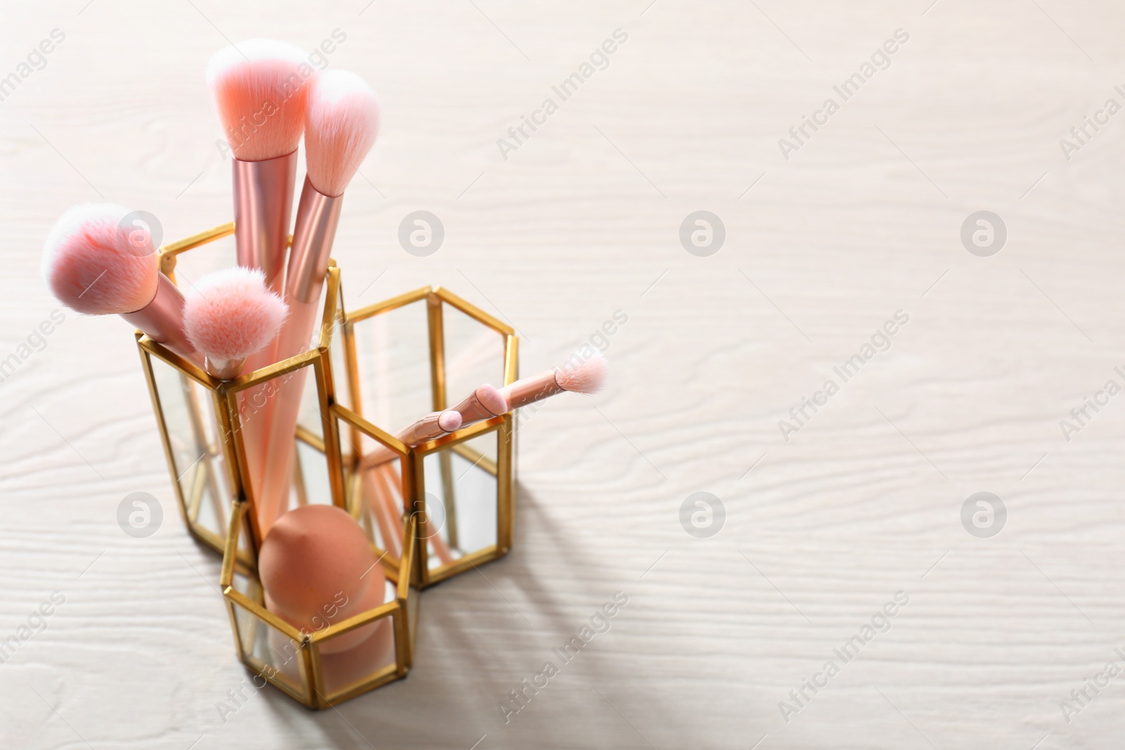 Photo of Organizer with makeup brushes and sponge on table. Space for text