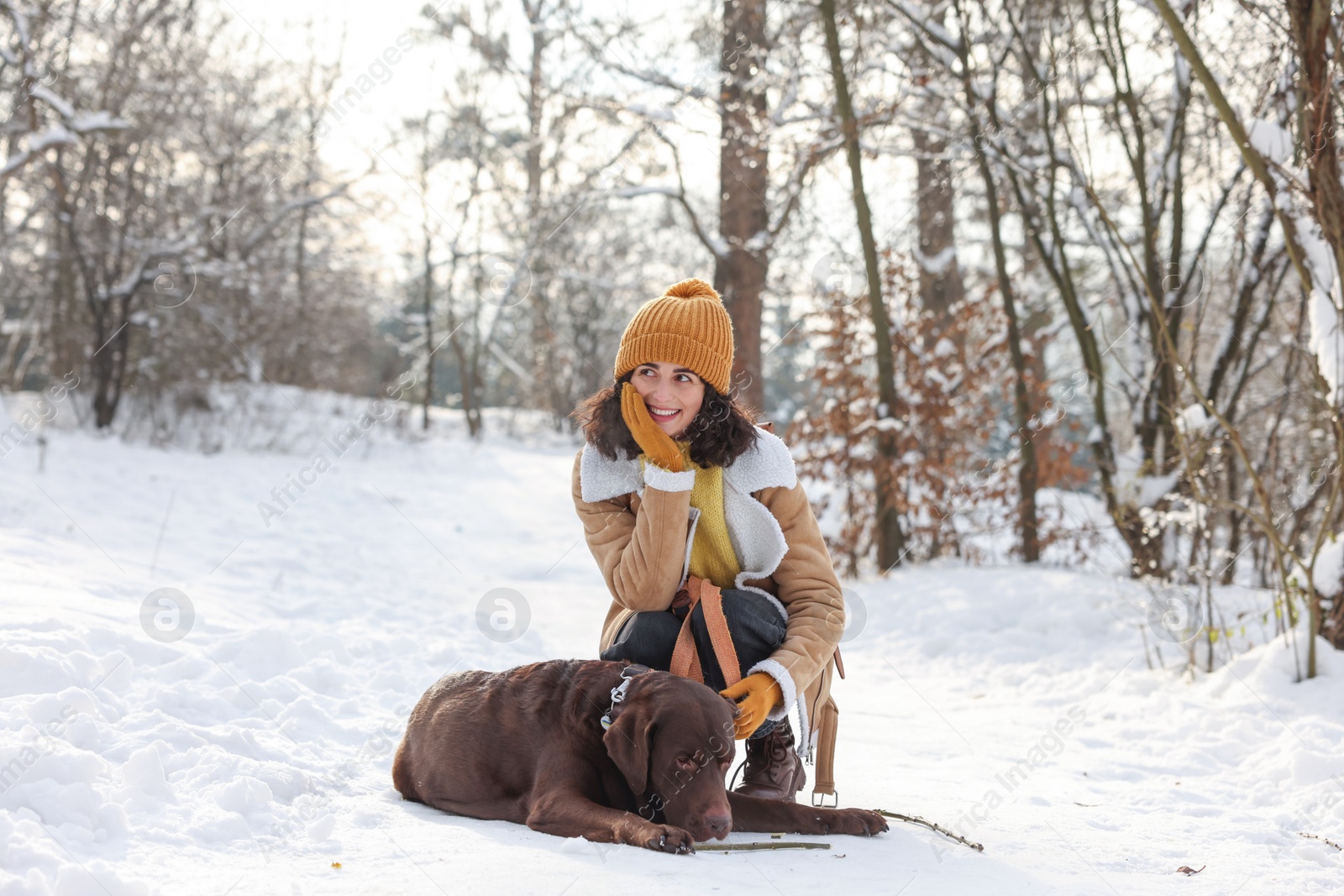 Photo of Woman with adorable Labrador Retriever dog in snowy park