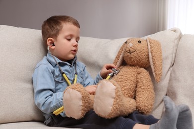 Photo of Cute little boy playing with stethoscope and toy bunny at home. Future pediatrician
