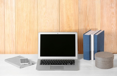 Photo of Laptop with blank screen at table indoors. Mock up for design