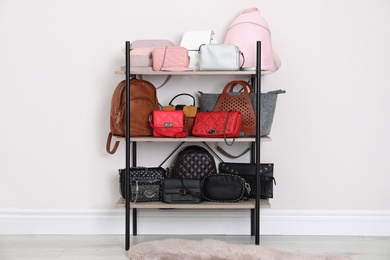 Photo of Shelving unit with stylish purses near white wall. Element of dressing room interior