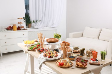 Photo of Dishes with different food on table in living room. Luxury brunch
