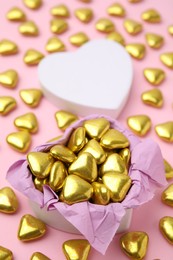 Box and delicious heart shaped candies on pink background