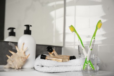 Light green toothbrushes in glass holder on table
