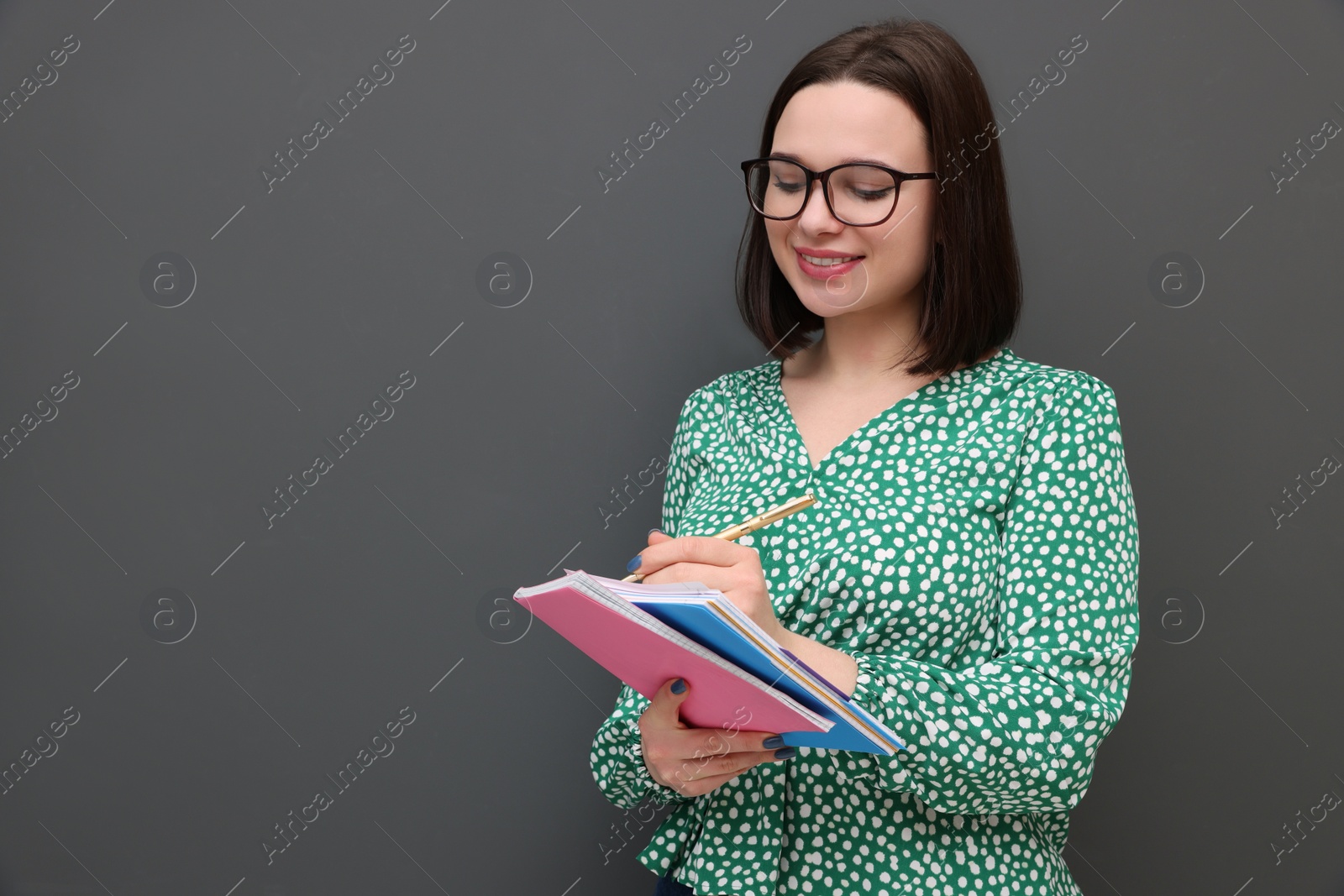 Photo of Happy young intern with notebooks and pen on grey background. Space for text