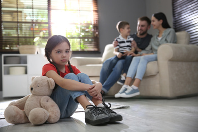 Photo of Unhappy little girl feeling jealous while parents spending time with her brother at home