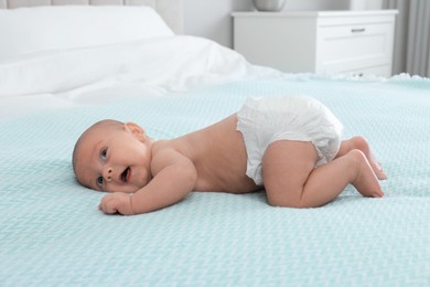 Cute little baby in diaper on bed at home