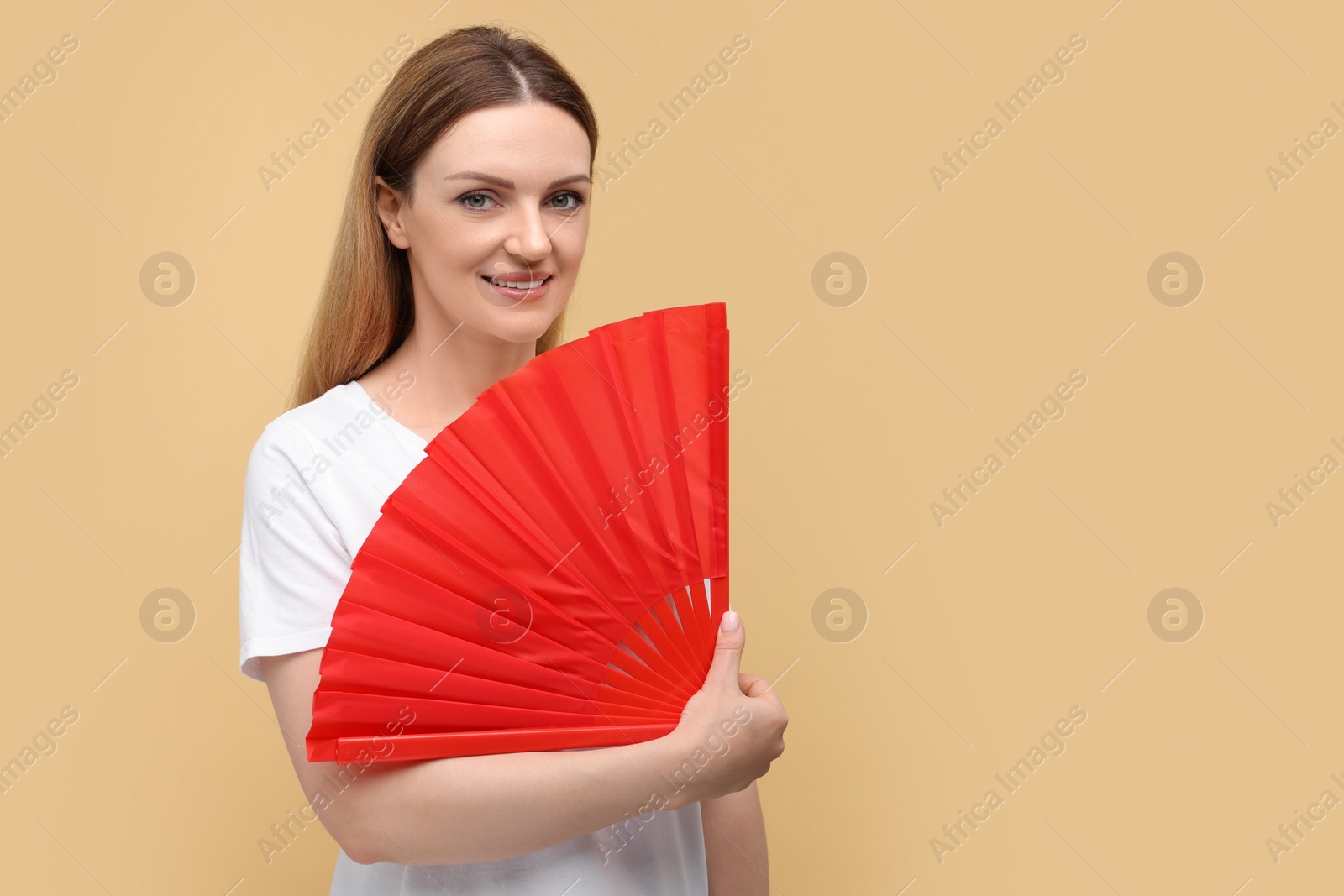 Photo of Happy woman with red hand fan on beige background. Space for text