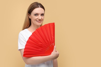 Photo of Happy woman with red hand fan on beige background. Space for text