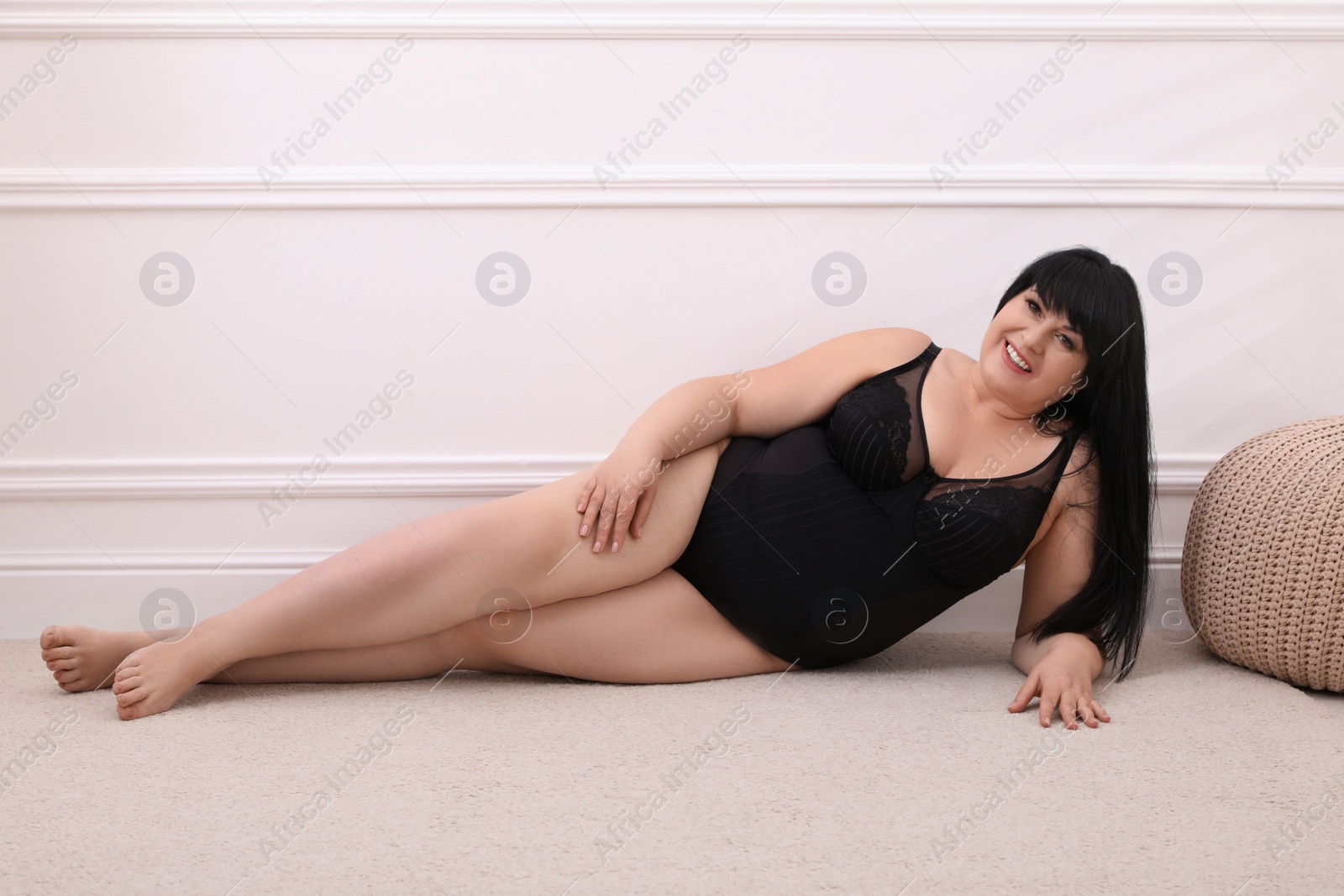 Photo of Beautiful overweight woman in black underwear posing at home. Plus-size model
