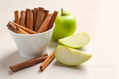 Fresh apples and cinnamon sticks on table