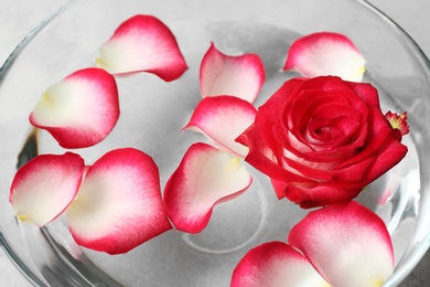 Photo of Glass bowl with aroma spa water, rose and petals, closeup