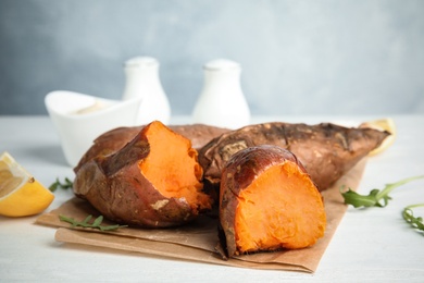 Photo of Delicious baked sweet potatoes on white table