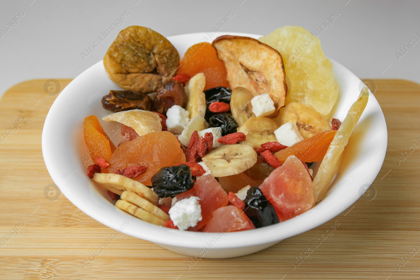 Photo of Bowl with different dried fruits on white background, closeup