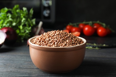 Photo of Buckwheat grains in bowl on wooden table