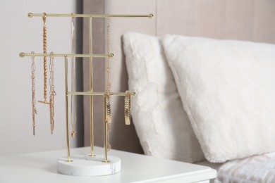 Photo of Interior element. Holder with set of luxurious jewelry on white nightstand in bedroom