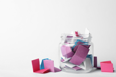 Photo of Glass jar full of folded paper sheets on white background