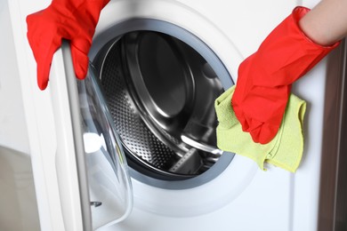 Photo of Woman cleaning washing machine with rag, closeup