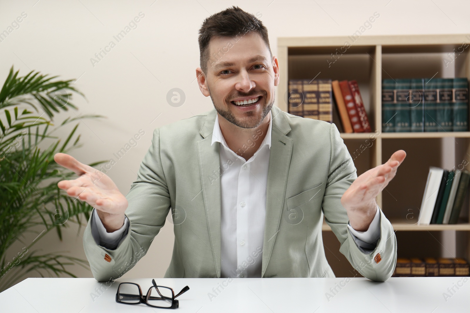 Photo of Happy businessman conducting webinar at desk in office, camera view