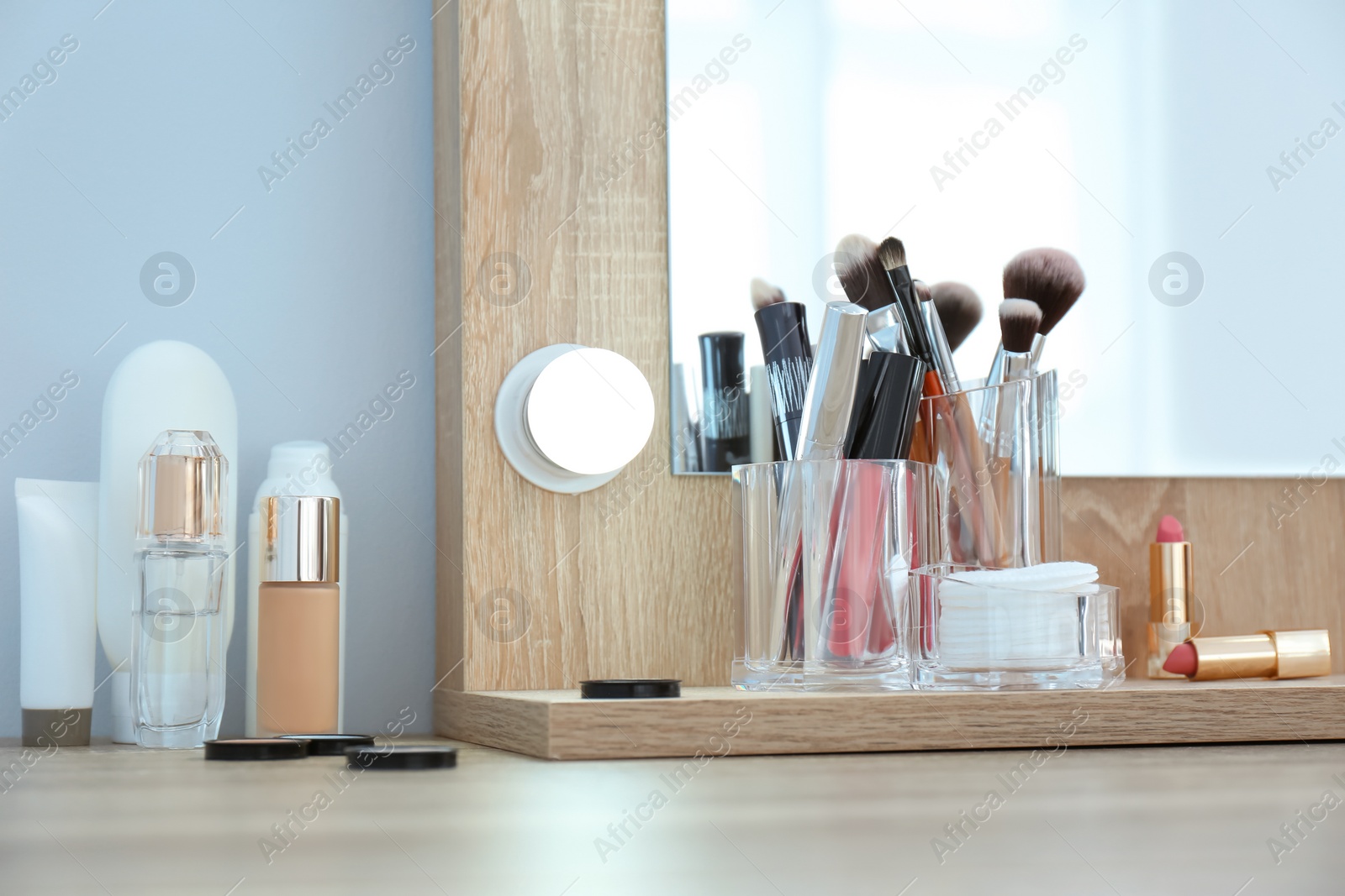 Photo of Organizer with cosmetic products for makeup on table near mirror