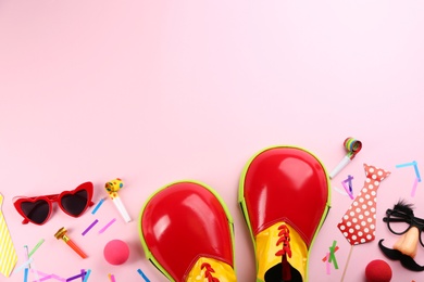 Photo of Flat lay composition with clown shoes and accessories on pink background. Space for text