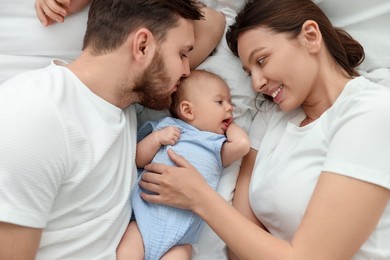 Happy family. Parents with their cute baby on bed, top view