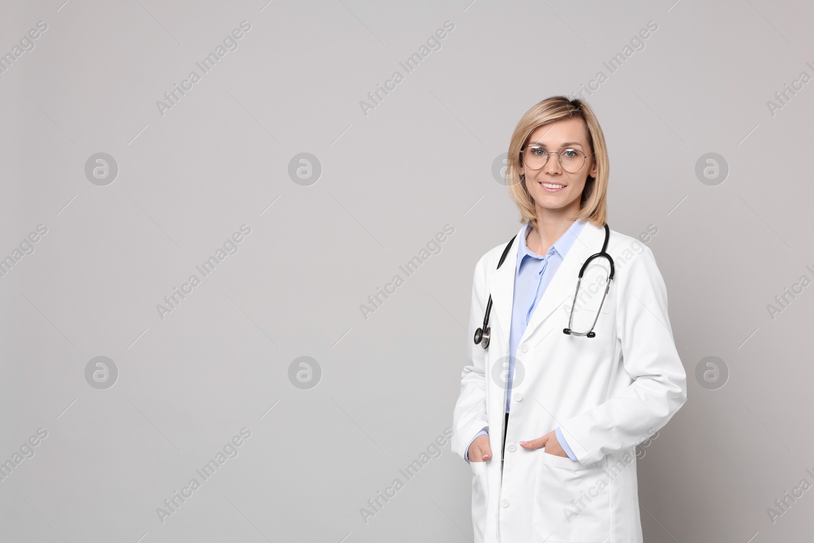 Photo of Smiling doctor on grey background. Space for text