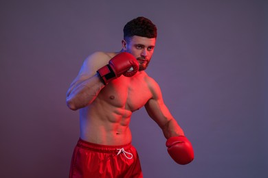 Photo of Man in boxing gloves fighting on color background