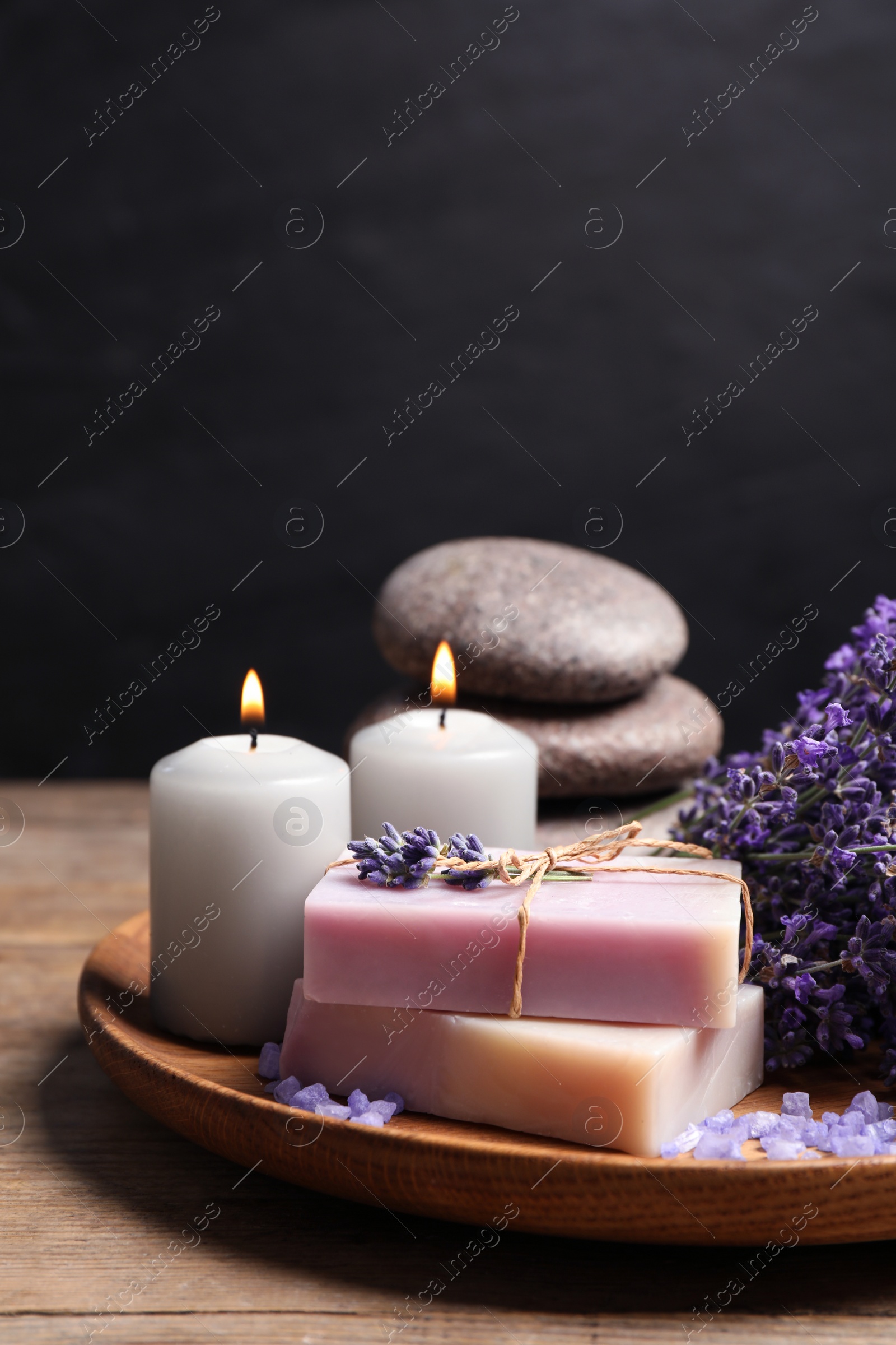 Photo of Burning candles, stones, soap bars and lavender flowers on wooden table