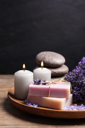 Burning candles, stones, soap bars and lavender flowers on wooden table