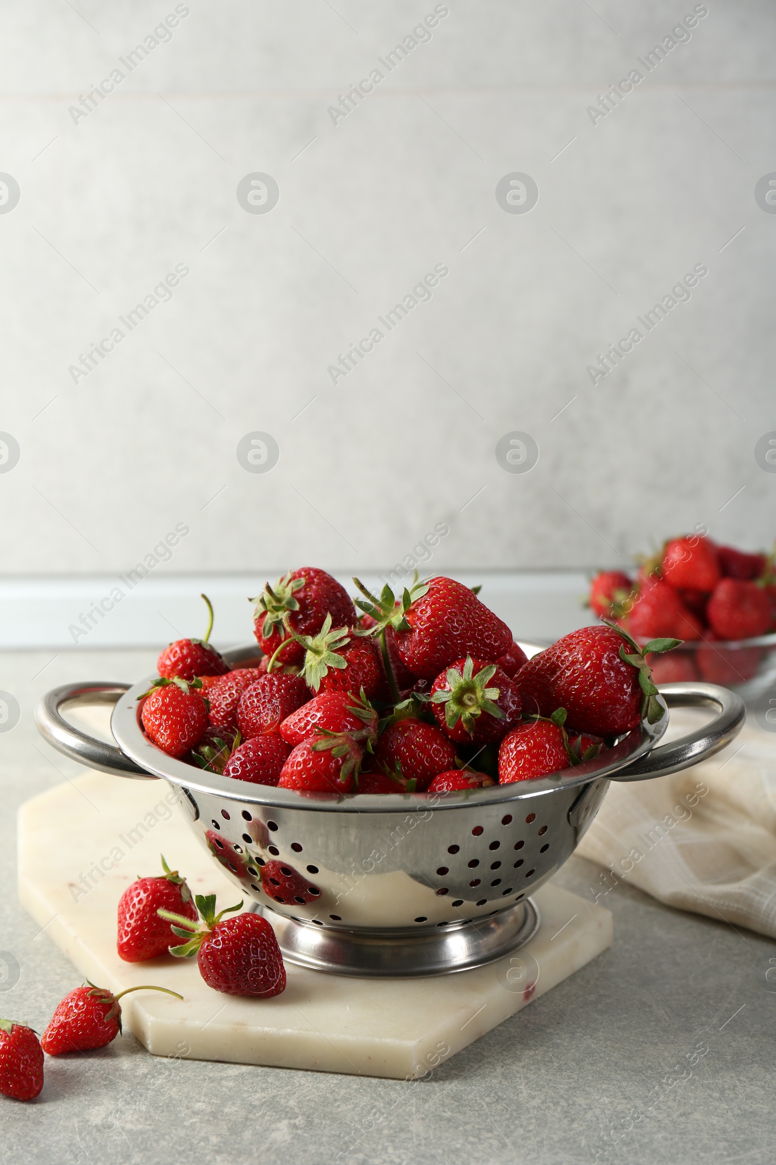 Photo of Metal colander with fresh strawberries on grey countertop